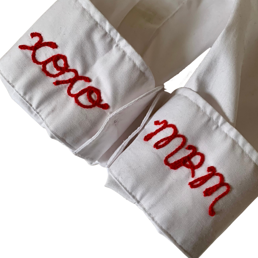 White button up shirt sleeve with xoxo and initials in red lettering embroidered with custom chain stitch embroidery