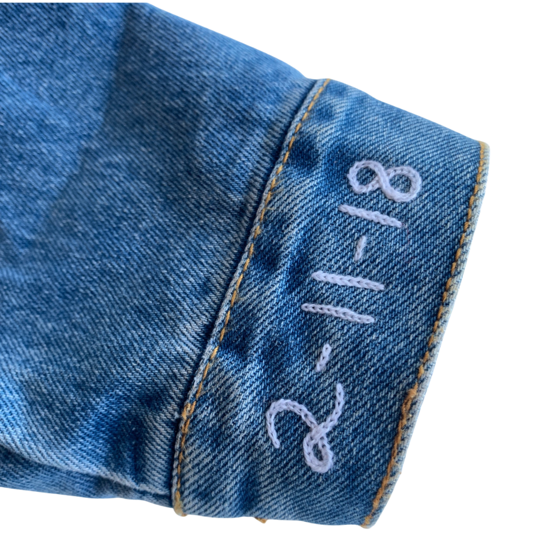 Jean jacket sleeve with a special date embroidered with custom chain stitch embroidery.